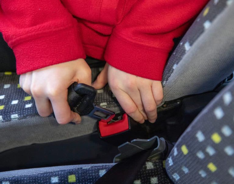 Gros plan d'un enfant attachant sa ceinture de sécurité dans un bus